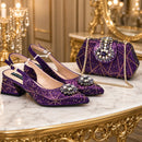 A pair of sparkling purple slingback heels with jeweled embellishments and a matching purple quilted handbag with a chain strap, displayed on a marble and gold console table in an ornate room, Obroi