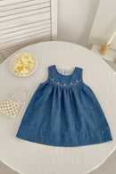 Blue denim dress on a round white table with decorative items, Obroi