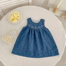 Blue denim dress on a round white table with decorative items, Obroi
