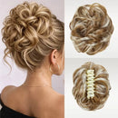 A blonde and brown synthetic updo hairpiece shown worn on a model's head from the back, plus two close-up views of the hairpiece itself on a light background. The hairpiece has a cream-colored claw clip closure, Obroi