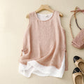 A sleeveless dusty pink linen top with a layered white ruffled hem, displayed on a wooden hanger on a beige background with a matching handbag and shoes as styling props, Obroi