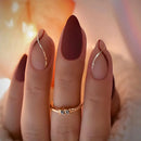 Obroi Close-up of a hand with red nail polish wearing a gold ring against a blurred background