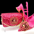 Pink glittery handbag with gold flower design and matching pink high heels on a black background, Obroi
