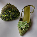 Green embellished clutch and shoe on a light gray background, Obroi