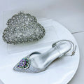 Silver high-heeled shoe with decorative embellishments on a white surface, Obroi