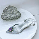 Silver high-heeled shoe with decorative embellishments on a white surface, Obroi