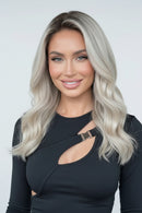 A wavy wig with a silver and ash blonde ombre color, shown on a model on the left and on a mannequin head on the right, with a third view showing the back of the hair, Obroi