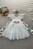 White lace dress with pink floral sash on a gray surface, Obroi