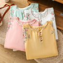 Four colorful tops with floral embroidery on a woven mat, Obroi