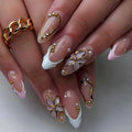 Close-up of hands with decorative nails featuring gold and white designs, Obroi
