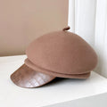 Brown beret with a textured visor on a white surface, Obroi