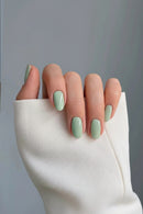 Hand with light green nail polish on a neutral background, Obroi