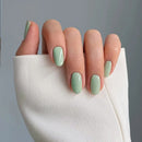 Hand with light green nail polish on a neutral background, Obroi