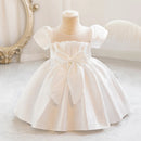 White baby dress on a mannequin with a decorative mirror in the background, Obroi