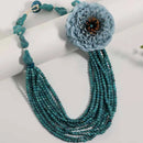 Turquoise beaded necklace with a large blue flower pendant on a white background, Obroi