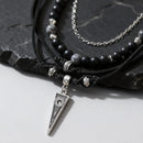 Black beaded necklace with silver pendant on a dark stone surface, Obroi
