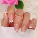 Hand with pink and gold nail design and a ring, with a blurred pink flower in the background, Obroi