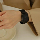 A close-up of a person's wrist wearing a black smartwatch with a black mesh band, styled with a beige trench coat sleeve, Obroi