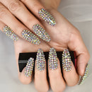 Hand with ornate nail art featuring rhinestones on a neutral background, Obroi