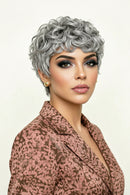 Woman with styled gray hair wearing a patterned top on a light background, Obroi