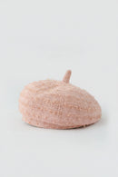 A light pink textured bouclé beret hat with a short top handle, photographed on a clean light gray background, Obroi