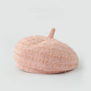 A light pink textured bouclé beret hat with a short top handle, photographed on a clean light gray background, Obroi