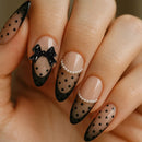 Nails with black polka dot and bow design on a beige background, Obroi
