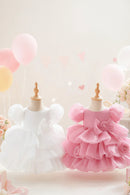 Two toddler girl's formal dresses displayed on mannequins, one white and one pink, both with tiered ruffle skirts, puffy sleeves, and large fabric bows. The text 'Obroi' appears in the top left corner.
