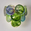 Colorful glass wall art with circular shapes on a plain background, Obroi