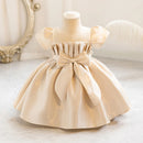Beige dress on a mannequin with a decorative bow, set against a neutral background, Obroi