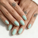 Close-up of hands with light green nail polish on a white background, Obroi