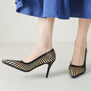 Black high-heeled shoes with mesh design worn by a person in a blue skirt, Obroi
