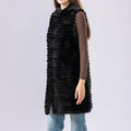 Person wearing a long black fur vest on a plain background, Obroi