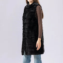 Person wearing a long black fur vest on a plain background, Obroi