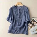 Blue embroidered blouse on a hanger with a beige background, Obroi