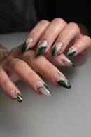 Close-up of a hand with green and gold nail art on a neutral background, Obroi