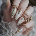 Decorative nails with gold and turquoise accents on a hand wearing lace sleeves, Obroi