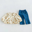 A toddler girl's two-piece clothing set featuring a cream-colored long-sleeve blouse with a woodland animal print and a matching blue denim capri pants, laid flat on a light gray background, Obroi