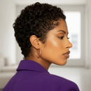 Woman with short, styled hair wearing a purple shirt in a neutral setting, Obroi