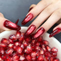 Hand with red nail polish holding a bowl of pomegranate seeds, Obroi