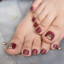 Close-up of toes with maroon nail polish and gold sequins on a soft fabric background, Obroi