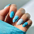 Hand with blue and white nail design against a neutral background ,Obroi