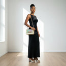 Woman in a black dress holding a clutch in a minimalistic setting, Obroi
