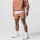 Person wearing a brown tracksuit with white sneakers on a light gray background, Obroi