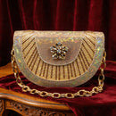 Gold beaded handbag with a brooch on a red velvet background, Obroi