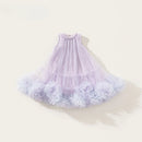 A sleeveless toddler party dress in lavender and light purple, featuring a pleated tulle bodice and a layered ruffled tulle skirt with flower-like ruffles at the hem, displayed on a light beige background, Obroi