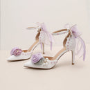 White high-heeled shoes with floral and bow decorations on a light background, Obroi