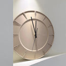 A minimalist round wall clock with a beige and cream color scheme, featuring black hands and a small gold center accent, mounted on a light gray wall, Obroi