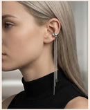 Close-up of a woman wearing a silver earring with dangling chains, Obroi