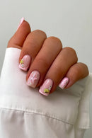 Hand with pink nail art featuring starfish and shell designs on a white background, Obroi